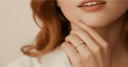 Close-up of a person wearing a ring on a neutral background